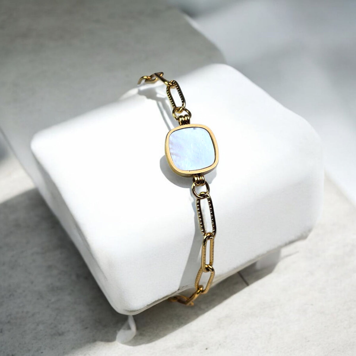 Zoom sur le connecteur carré en nacre blanche du bracelet Némora, bijou lumineux en acier doré