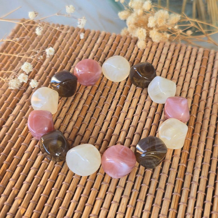 Bracelet femme avec perles irrégulières effet résine marbrée dans des tons crème, rose poudré et marron.