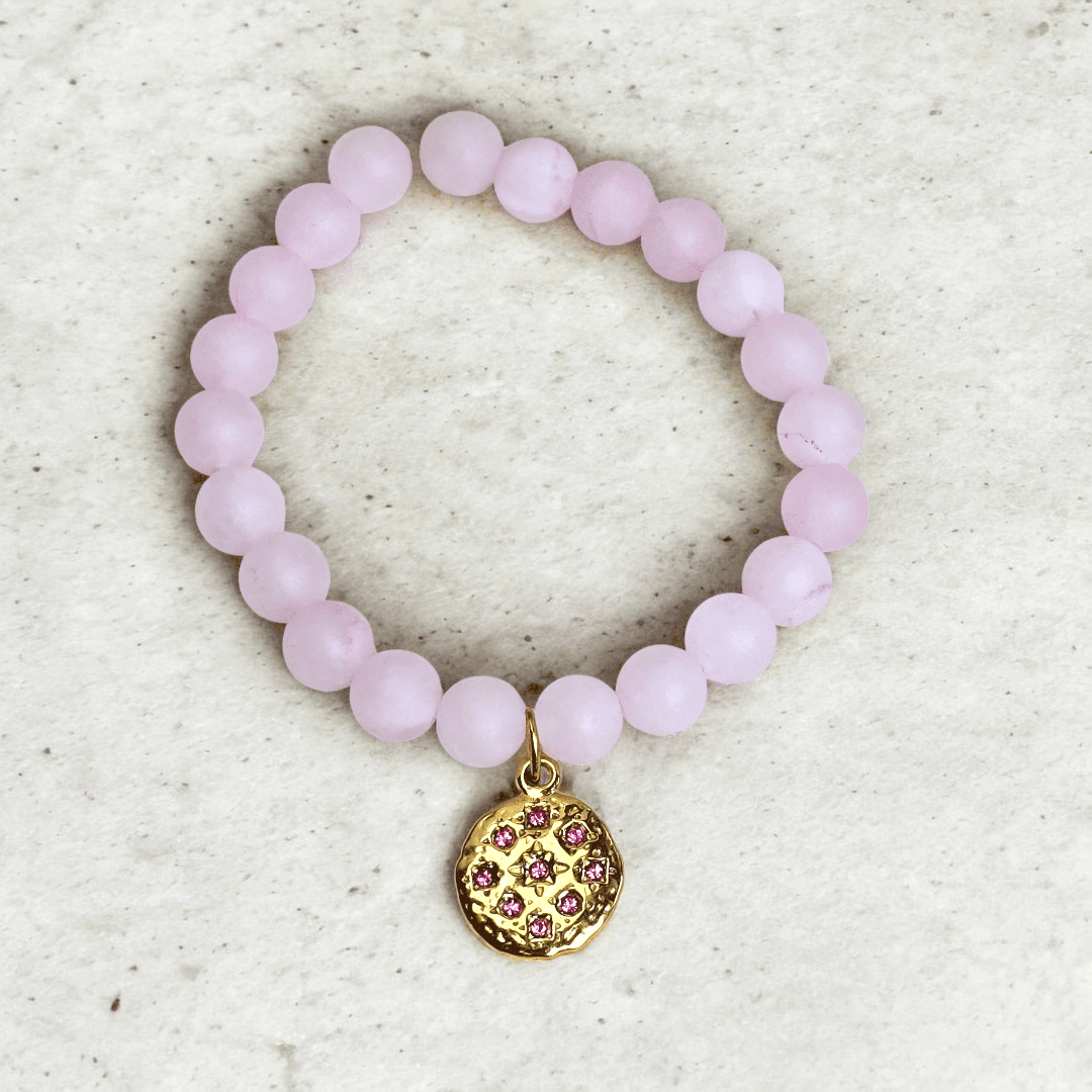 Bracelet en perles de quartz rose porté au poignet avec médaillon martelé doré et strass rose, bijou artisanal Zateka