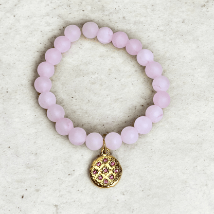 Bracelet en perles de quartz rose porté au poignet avec médaillon martelé doré et strass rose, bijou artisanal Zateka