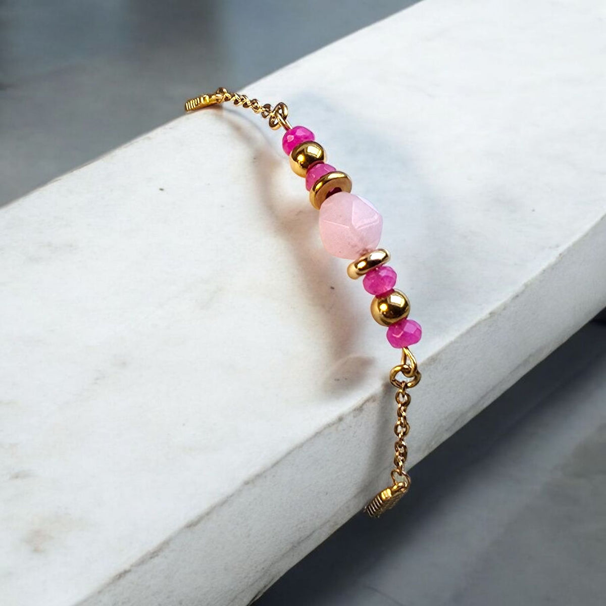 Bracelet Tyria porté au poignet avec perle de quartz rose et perle dorée en acier inoxydable