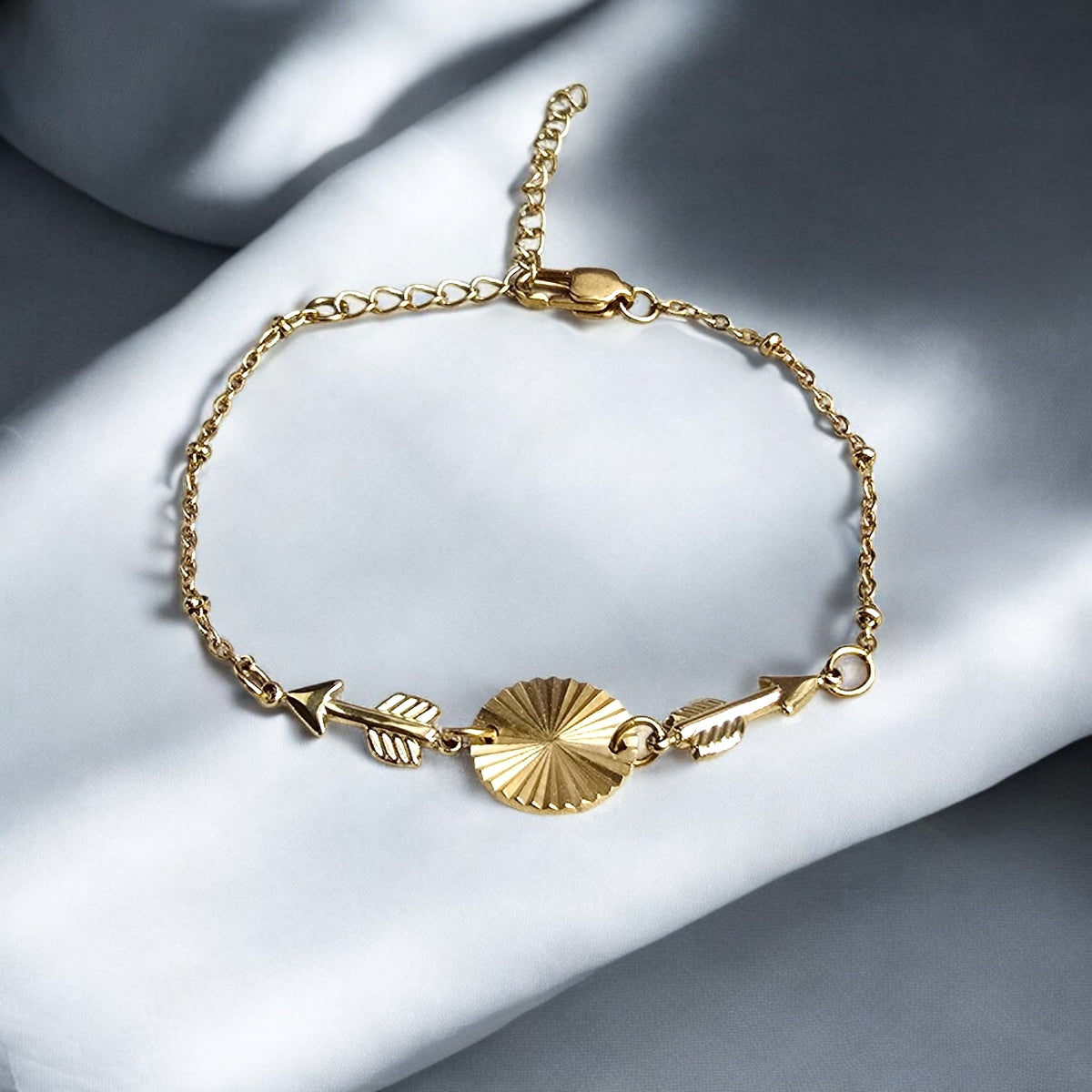 Bracelet doré graphique porté au poignet avec cercle texturé et flèches fines, bijou lumineux pour femme