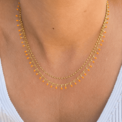 Collier femme à double chaîne avec gouttes corail pour un style estival.