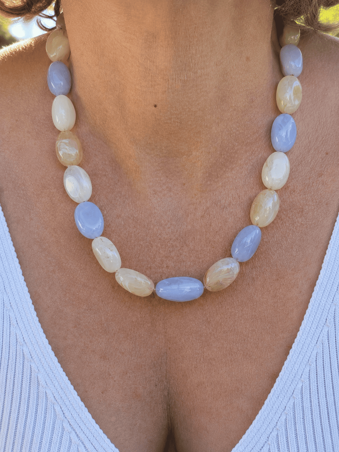 Collier bleu pastel et crème avec perles ovales marbrées et chaîne dorée.