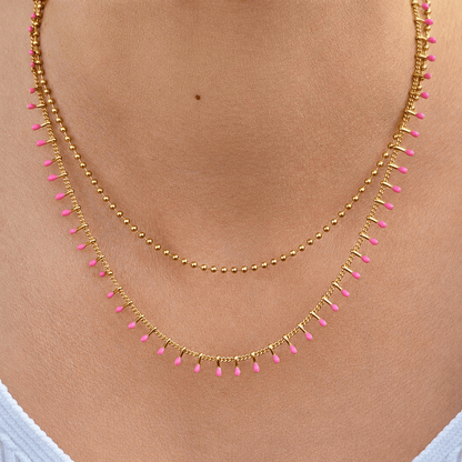Collier coloré femme avec chaîne bille dorée et détails rose fuchsia.