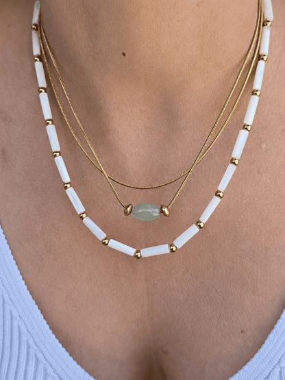 Collier acier inoxydable doré avec perles tubulaires blanches.