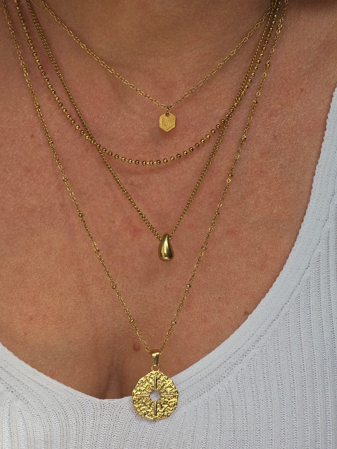 Collier fin doré MELITE porté en accumulation avec d’autres bijoux
