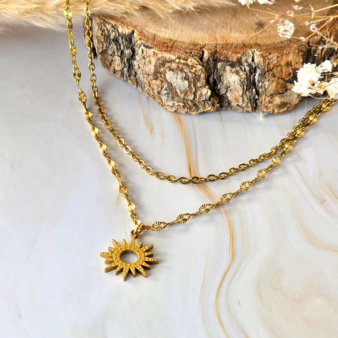 Détail du collier Melia doré à pendentif solaire sur fond clair
