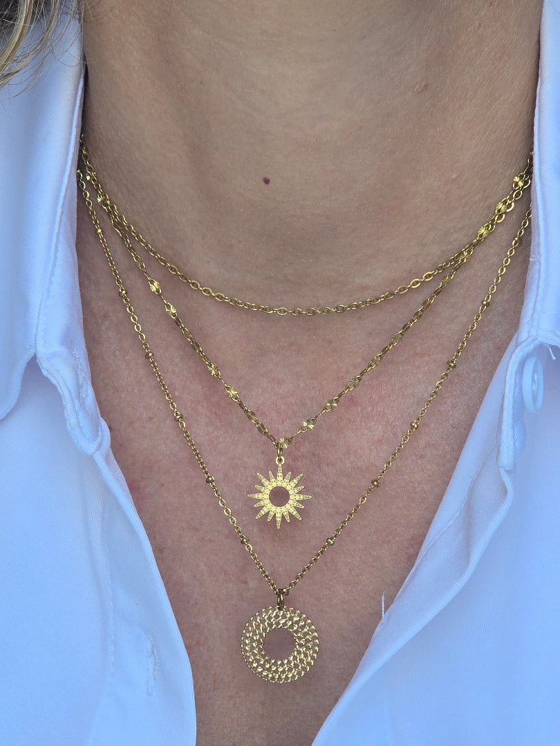 Collier ERIS porté en accumulation avec d’autres colliers dorés
