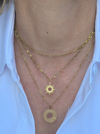 Collier ERIS porté en accumulation avec d’autres colliers dorés
