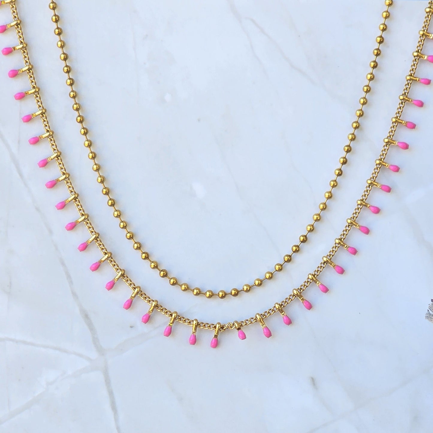 Collier double rang rose fuchsia en acier inoxydable doré.