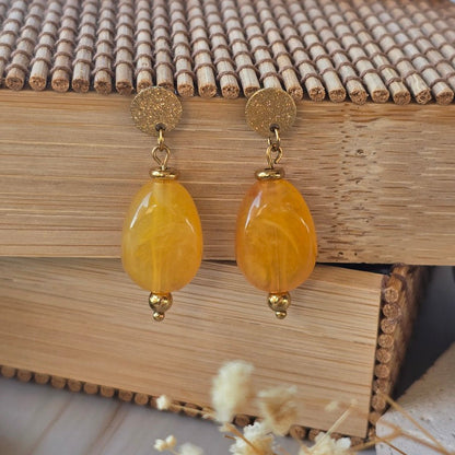 Puces d'oreilles orange doux et marron inspirées des nuances du bord de mer.
